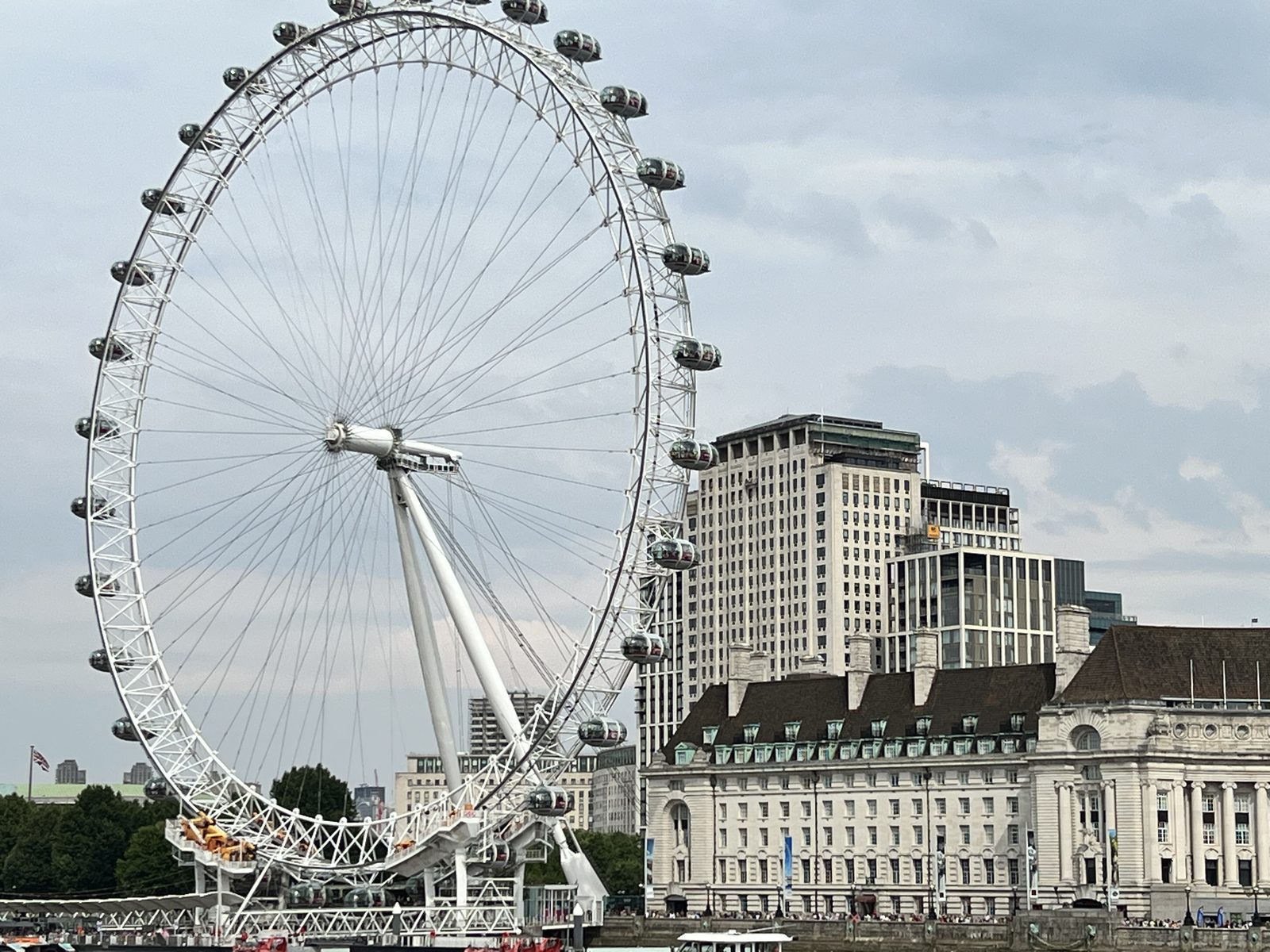 Ferris wheel beside a large historic building under a cloudy sky.